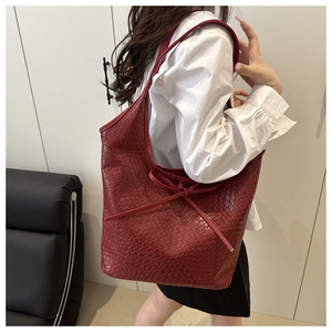 Deep red woven leather tote bag with bow detail worn by model for casual commute
