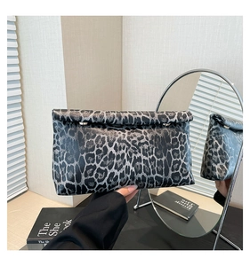 Dettaglio borsa leopardata con chiusura roll-top e bottoni a pressione metallici
