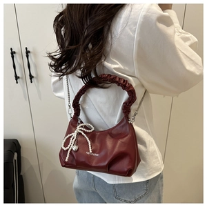 Detail of burgundy ruched shoulder bag with pearl bow and heart metal pendant