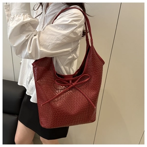 Detailed shot of red woven leather tote bag with a decorative bow on the shoulder