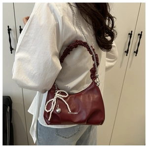 Detail of burgundy ruched hobo bag with pearl bow charm and silver chain strap