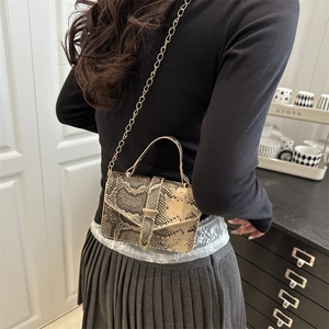 Snake pattern crossbody bag with gold chain strap and envelope flap shown on model