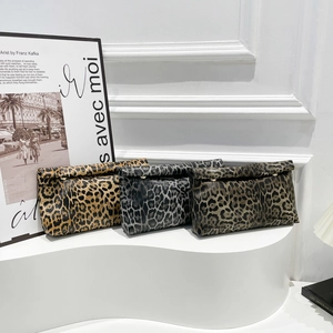 Three leopard print crossbody bags in various colors on a luxury display stand