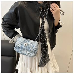 Détail du sac bandoulière en denim bleu clair avec texture losange effilochée et fermoir