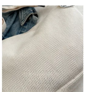 Close-up of white woven dumpling bag texture against blue denim background decor