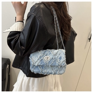 Détail du sac à bandoulière en jean bleu clair avec franges matelassées et fermoir