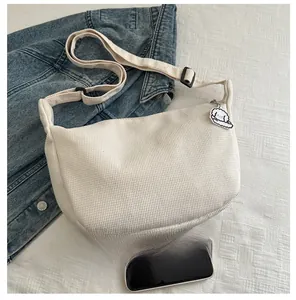 Detail of creamy white corduroy hobo bag with adjustable strap and cute dog charm