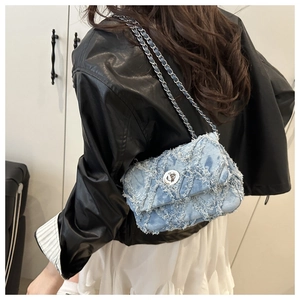 Détail du sac bandoulière en denim bleu clair avec matelassage effiloché et fermoir argenté