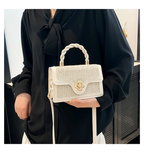 Detail of cream woven mini handbag featuring flower twist lock and braided handle