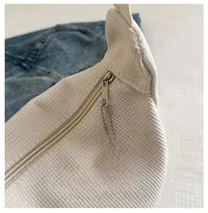 Close-up of white corduroy tote bag with silver zipper and cute cartoon dog charm
