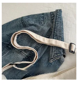 Detail of blue denim tote bag featuring a comfortable cream knitted adjustable shoulder strap