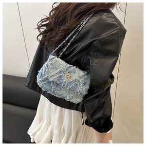 Détail du sac bandoulière en denim vieilli avec franges et bandoulière chaîne