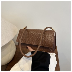 Detail of a brown woven texture leather shoulder bag with gold metal hardware
