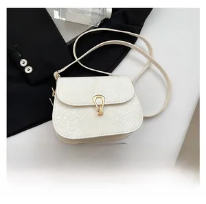 Détail du sac selle blanc avec texture motif serpent et boucle métallique dorée