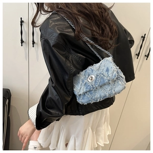 Détail du sac bandoulière en jean bleu clair avec surpiqûres et bords effilochés