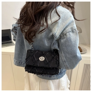 Détail du sac bandoulière en denim matelassé noir avec chaîne et fermoir argenté