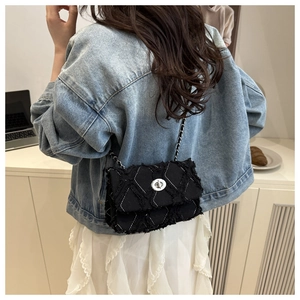 Détail du sac bandoulière en denim noir avec bordures effilochées et chaîne argent