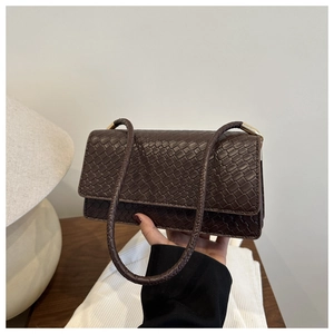 Close-up of brown woven leather shoulder bag with fine texture and golden metal buckle