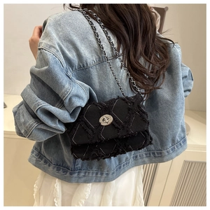 Détail du sac matelassé noir avec fermoir rotatif argenté et texture denim effiloché