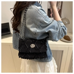 Détail du sac bandoulière matelassé noir avec chaîne argentée et texture en tissu vintage
