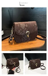 Détail du sac de selle marron foncé à motif serpent gaufré et boucle métallique dorée