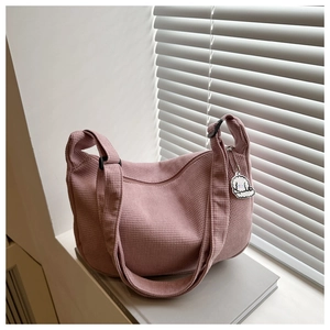 Detailaufnahme der pinkfarbenen Cord-Tasche mit süßem weißem Welpen-Anhänger