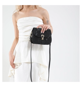 Detail of black snakeskin texture and gold horseshoe clasp on saddle crossbody bag