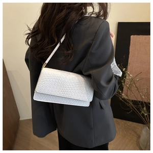 Detail view of the white woven leather shoulder bag showing texture and styling on model