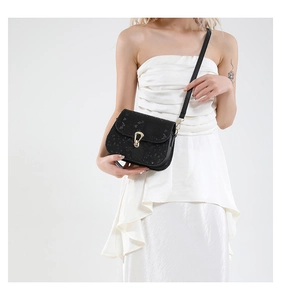 Détail du sac selle noir en cuir texturé avec boucle mors dorée et bandoulière fine