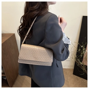 Beige woven shoulder bag shown on model in a minimalist modern fashion setting