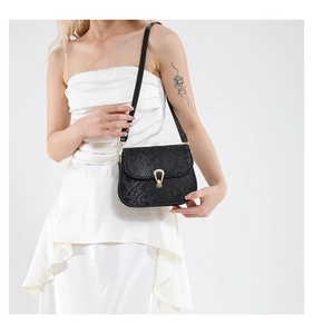 Close-up of black snake pattern texture and gold horseshoe buckle on the bag
