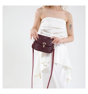 Détail du sac à bandoulière rouge foncé motif serpent avec fermoir tournant en U doré