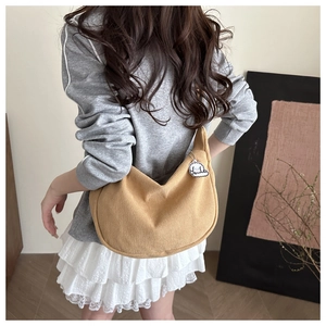 Detailed texture of brown corduroy hobo bag shown on model with cloud charm