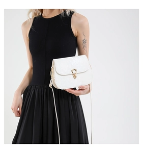 Détails du sac à main blanc en cuir texturé avec fermoir en métal doré porté par un mannequin