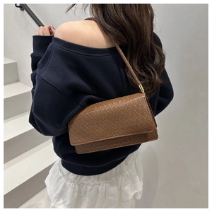 Detailed close-up of brown crocodile pattern texture on a minimalist shoulder bag