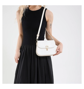 Close-up of white snake texture saddle bag with golden horseshoe clasp and slim strap