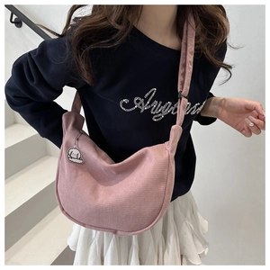 Detail der rosa Hobo-Tasche mit Waffelstruktur und süßem Anhänger am breiten Gurt