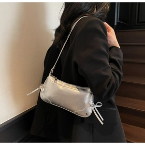 Detail of silver metallic shoulder bag with side bow tassels worn with a black blazer
