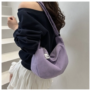 Close-up of purple corduroy crescent bag with a cute sheep pendant detail