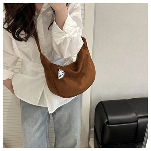 Sac bandoulière en velours côtelé marron avec breloque mouton porté par le mannequin