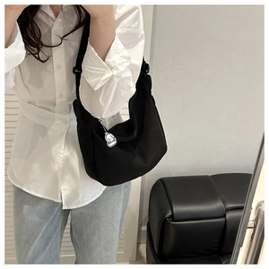 Détail d'un sac demi-lune en velours côtelé noir avec pendentif chien blanc et look décontracté