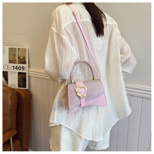 Gros plan du sac rose pailleté avec un fermoir floral doré sur rabat en cuir lisse