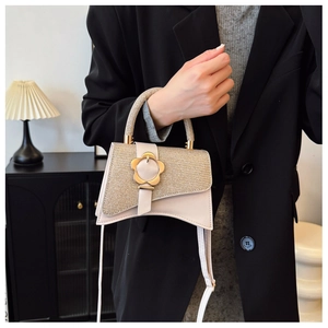 Dettaglio di una mini borsa chic in pelle crema con chiusura floreale dorata e metallo
