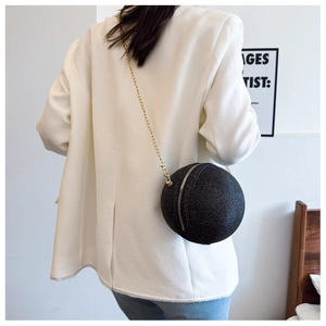 Close-up of a sparkling black spherical evening bag with elegant gold chain strap