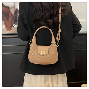 Detail of khaki woven texture handbag with gold twist lock on black blazer