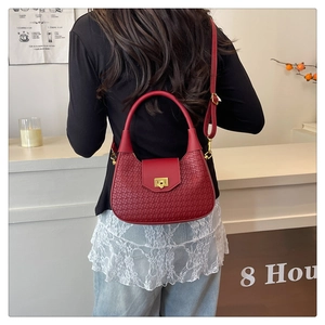 Detailed back view of a burgundy leather handbag with woven texture and gold clasp