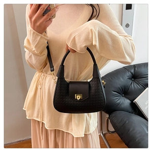 Detail of black woven texture handbag with golden square lock and hobo style design