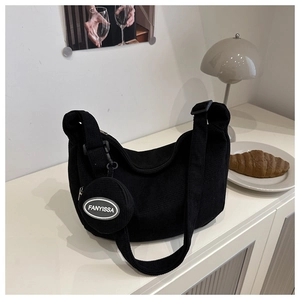 Detail of black corduroy hobo bag with matching mini round pouch on a minimalist background