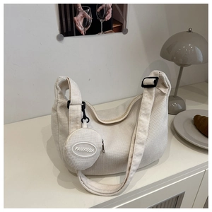 Detail of off-white waffle texture dumpling bag with adjustable strap and small coin purse