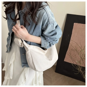 Detail of a minimalist off-white dumpling bag with textured fabric and mini round pouch